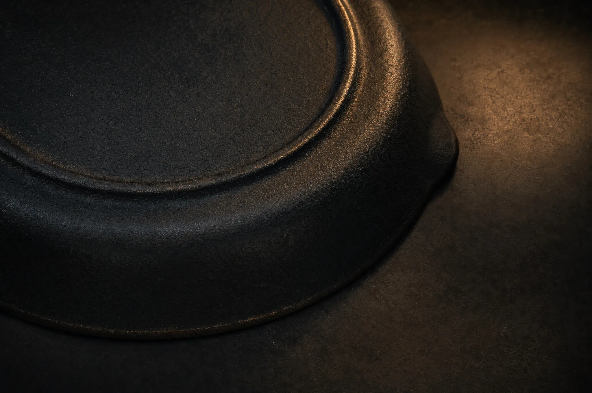 Raised heat ring on the underside edge of a vintage cast iron skillet in raking light